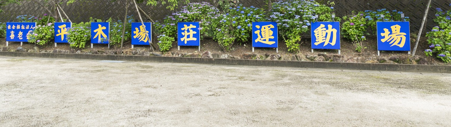擁壁に掲げられた「平木場荘 運動場」の看板